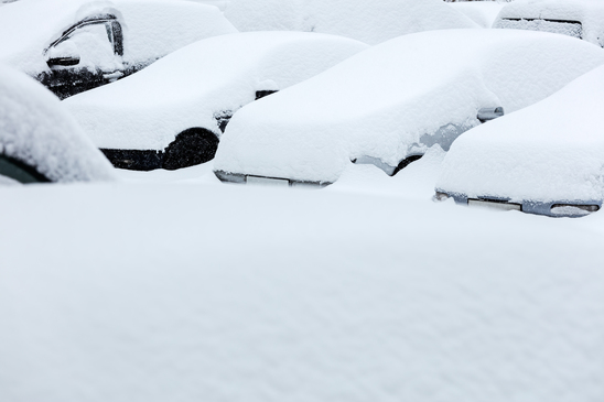 cars covered with snow in the parking lot during winter blizzard